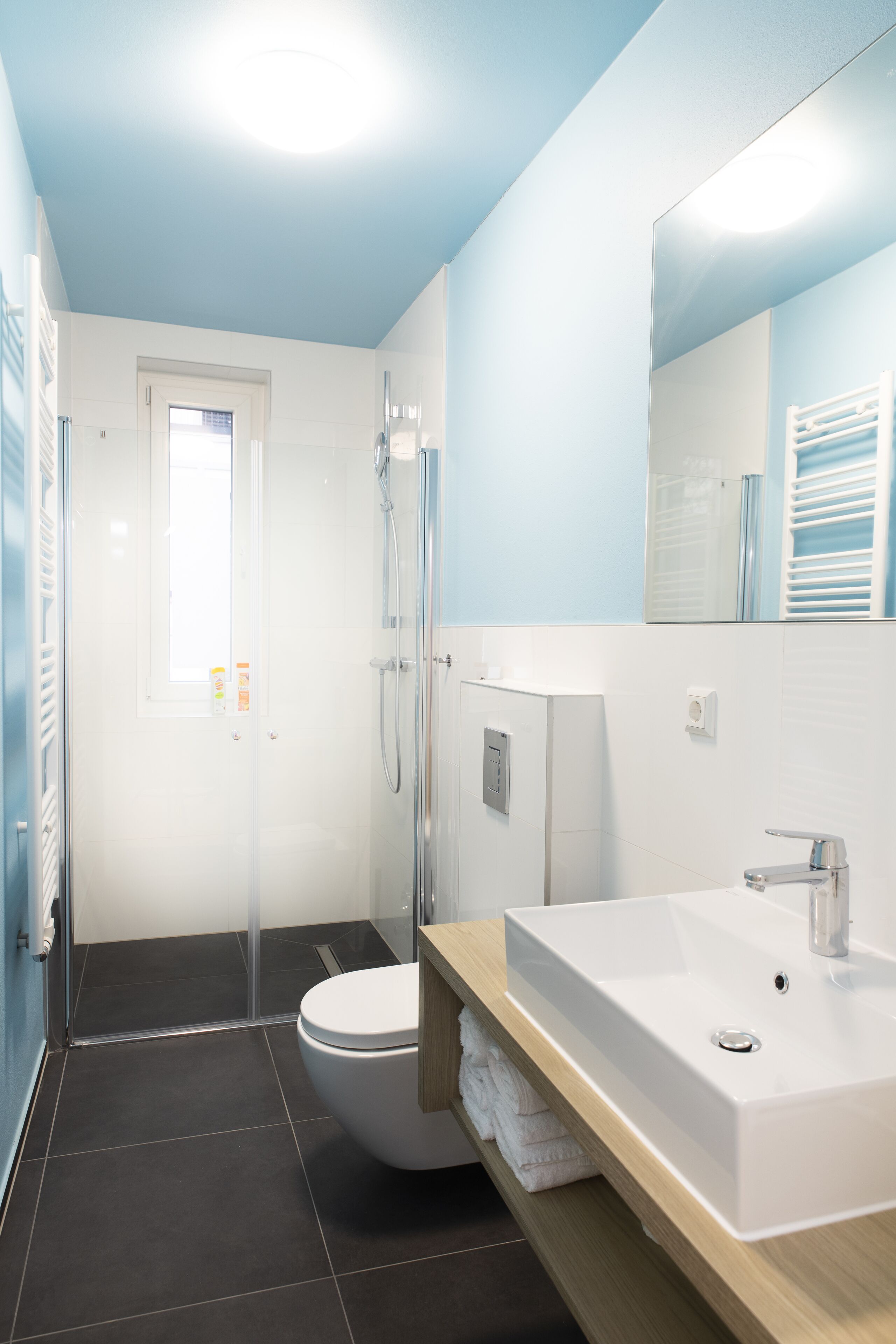 A modern bathroom with a white sink, mirror, and shower.