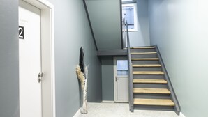 A staircase with wooden steps and a metal handrail, leading to a door with a number '2' sign. - Villa am Bahnhof (Fulda)