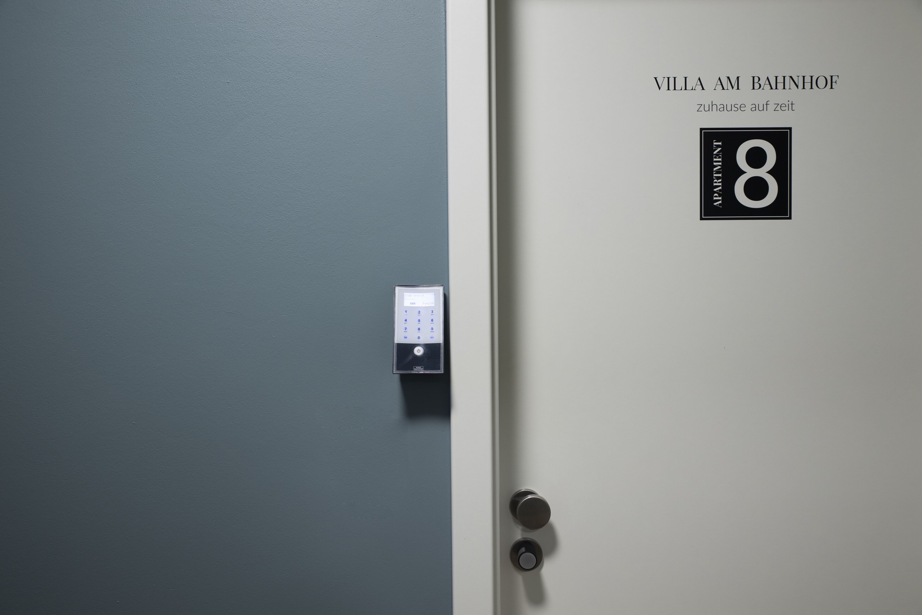 A door with a digital lock and a sign indicating "Villa Am Bahnhof" and "Apartment 8".