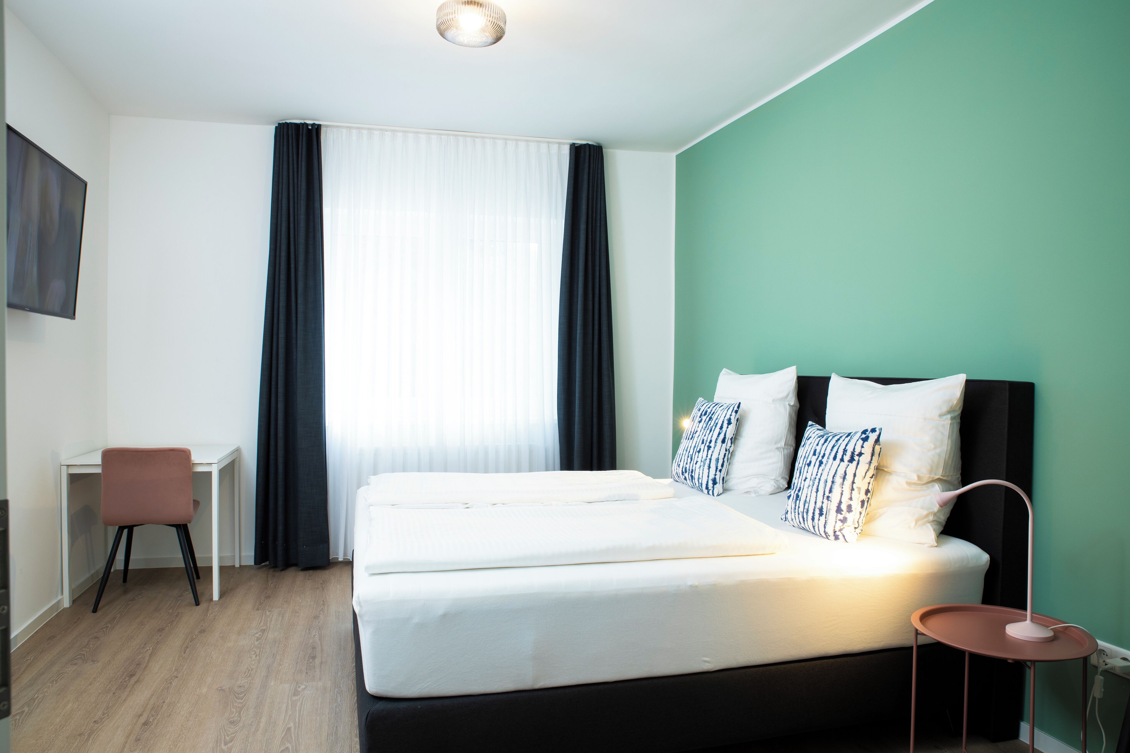 A hotel room with a bed, a desk, and a chair.