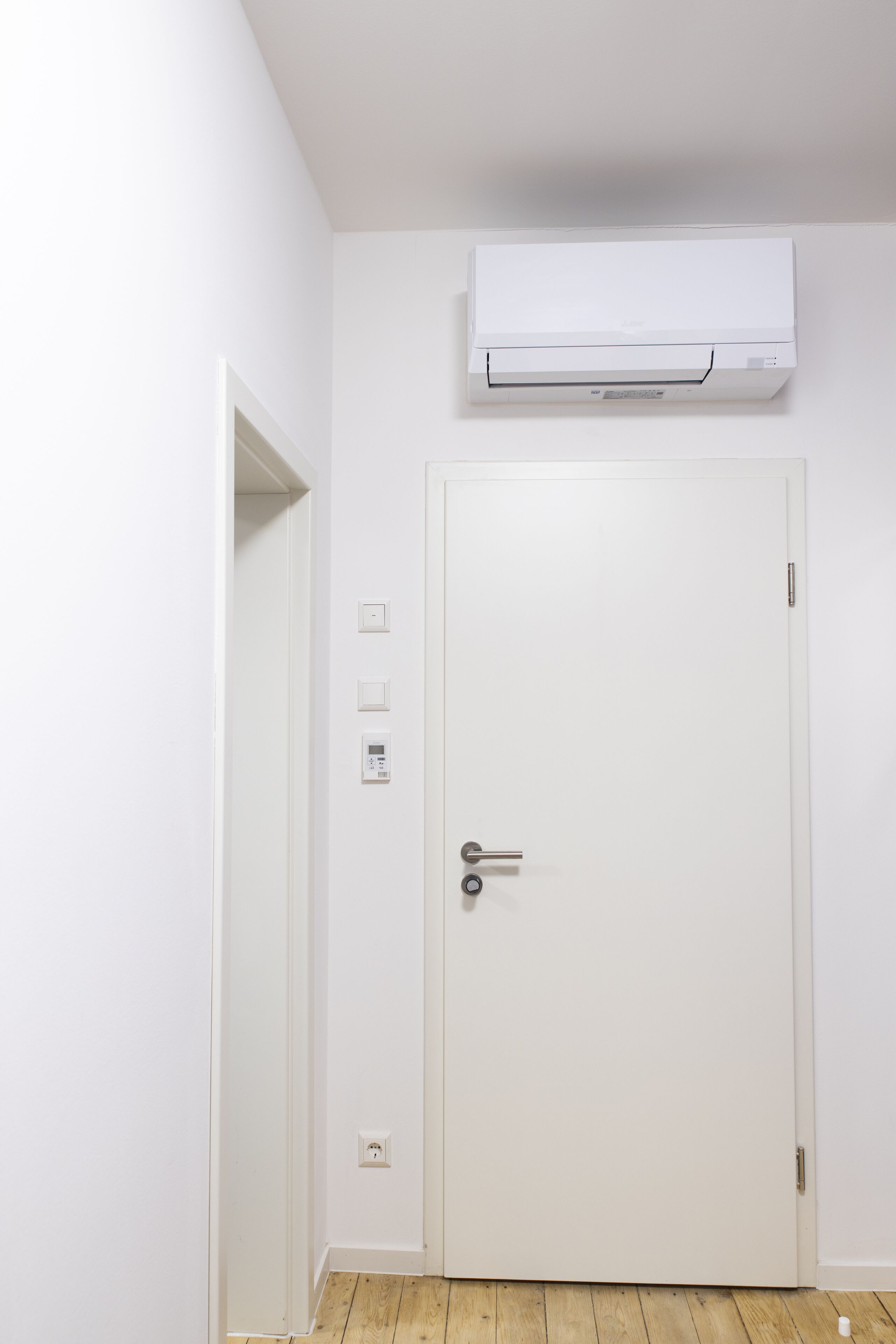Une porte blanche avec un climatiseur fixé au mur juste au-dessus.