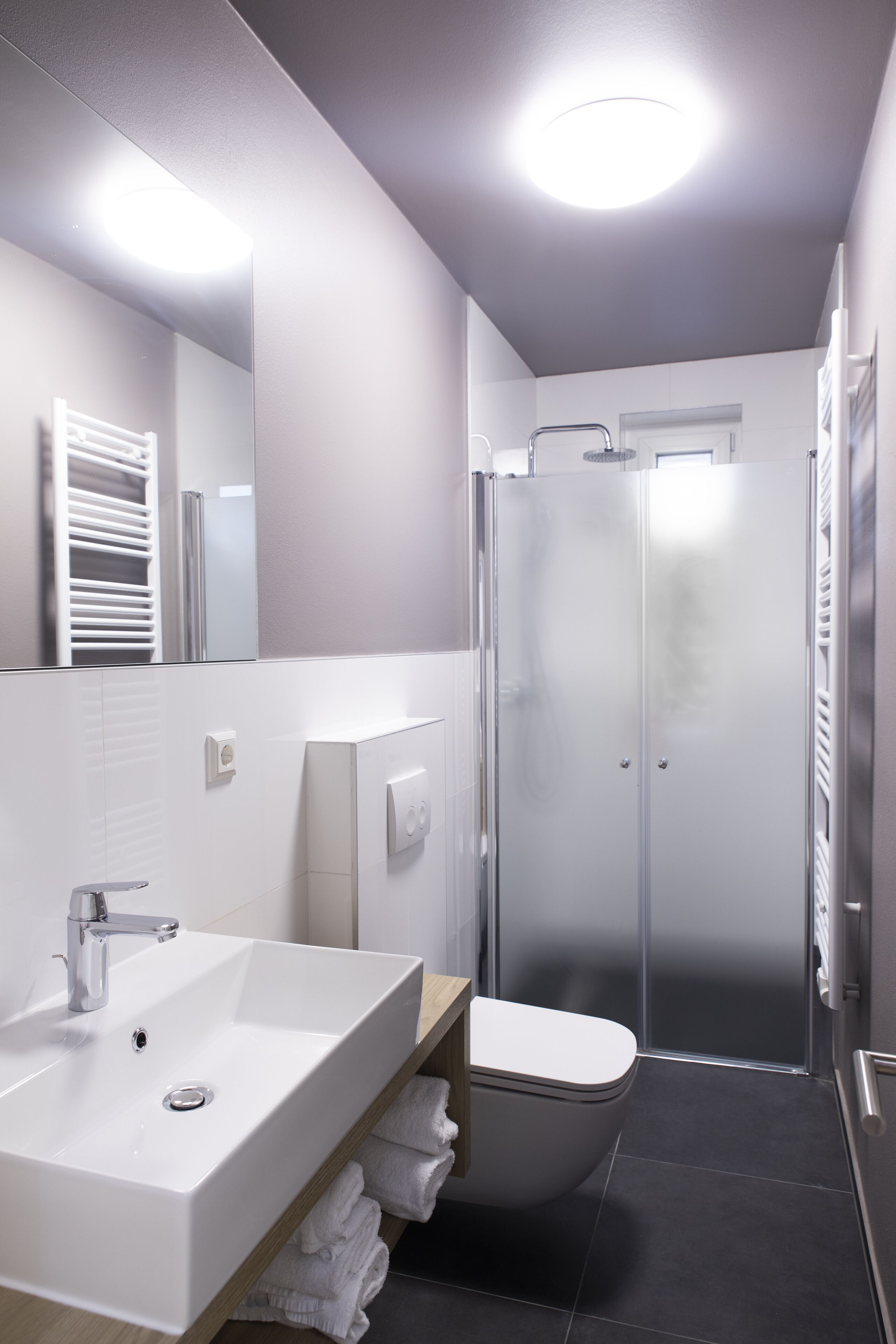 A modern bathroom with a white sink, mirror, and shower.