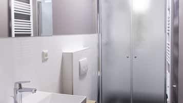 A modern bathroom with a white sink, mirror, and shower.