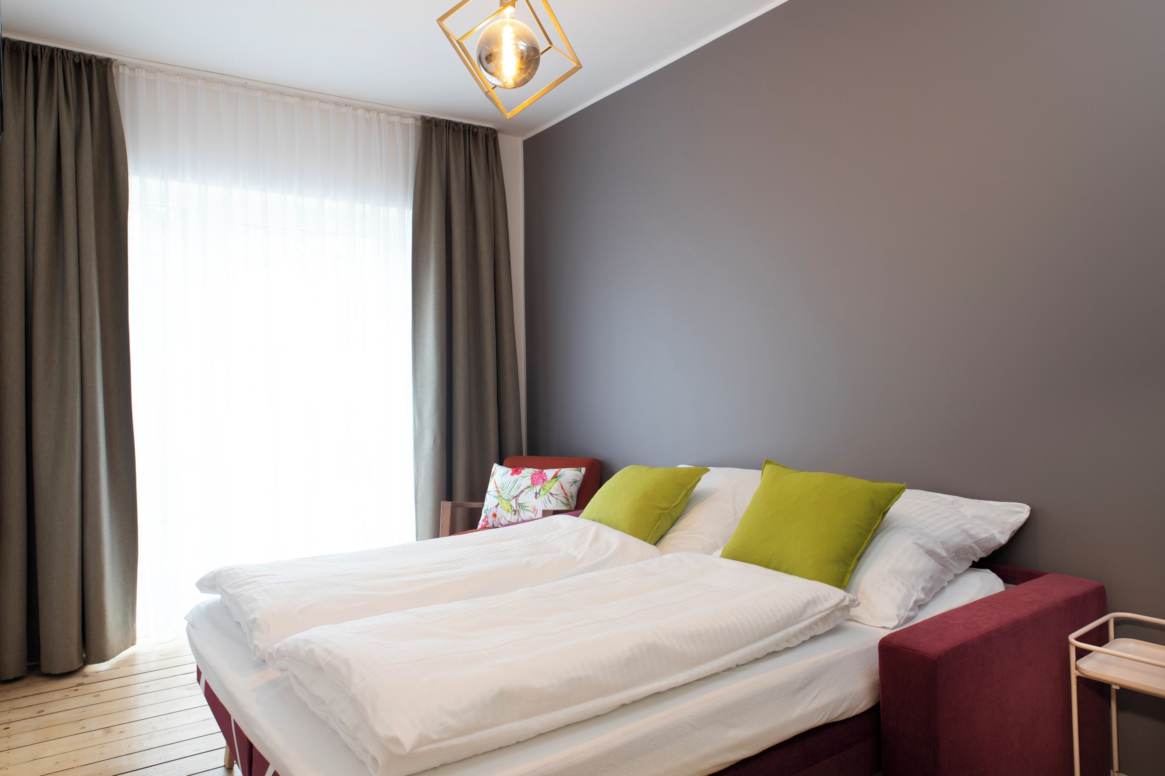 Een hotelkamer met een bed, gordijnen, een lamp en uitzicht op het landschap.