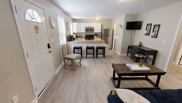 Un espacio habitable compacto con kitchenette, comedor y zona de estar con sofá y mesa de centro.