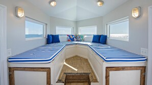 Una camera accogliente a tema nautico, con una panca al centro, ampie finestre e un soffitto in legno.