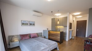 Ein modernes Schlafzimmer mit einem großen Bett, Nachttischen, einem Schreibtisch und einer Küchenzeile.