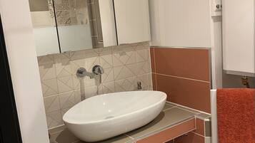 Une salle de bain avec un lavabo blanc, un miroir et un porte-serviettes.