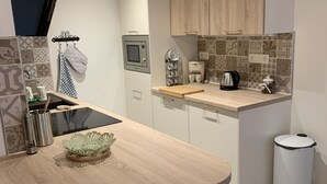 Una cocina moderna con encimera de madera, microondas, cafetera y cubo de basura.