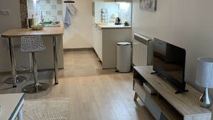 Una cocina moderna con zona de comedor, televisor y un pequeño espacio de estar.