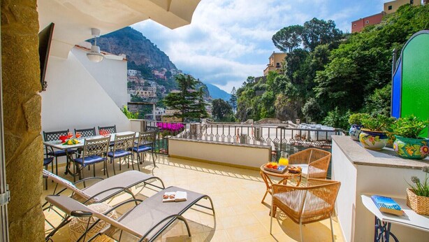 A terrace with outdoor seating, a table with a book and a glass, and potted plants. - Estate4home - Casa Nonna Mary (Positano)
