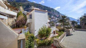 A coastal town with buildings, a balcony, and a mountainous backdrop. - Estate4home - Casa Nonna Mary (Positano)