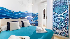 A bedroom with a bed, pillows, a nightstand, and a wall mural. - Estate4home - Casa Nonna Mary (Positano)