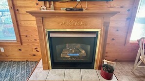 Una habitación con paneles de madera, una chimenea y un televisor de pantalla plana montado encima, además de un pequeño objeto decorativo sobre la repisa.