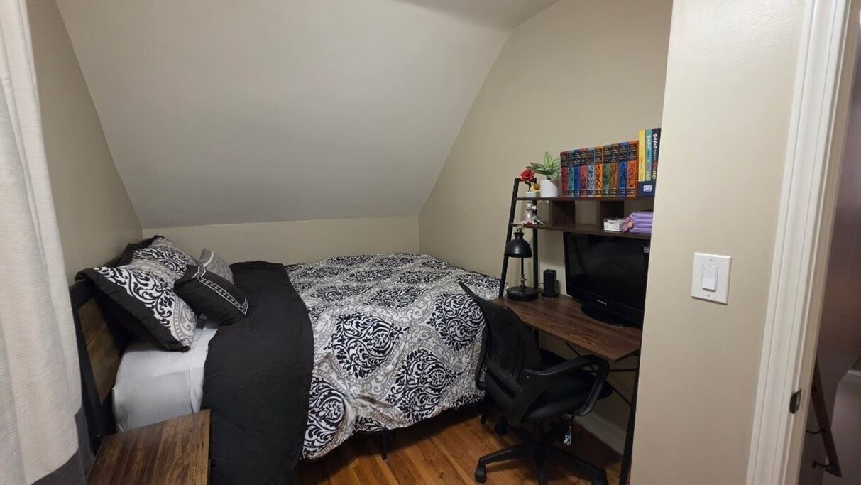 Un dormitorio con cama, escritorio, silla y estantería.