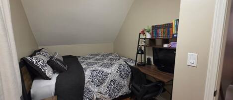 Une chambre à coucher avec un lit, un bureau, une chaise et une bibliothèque.