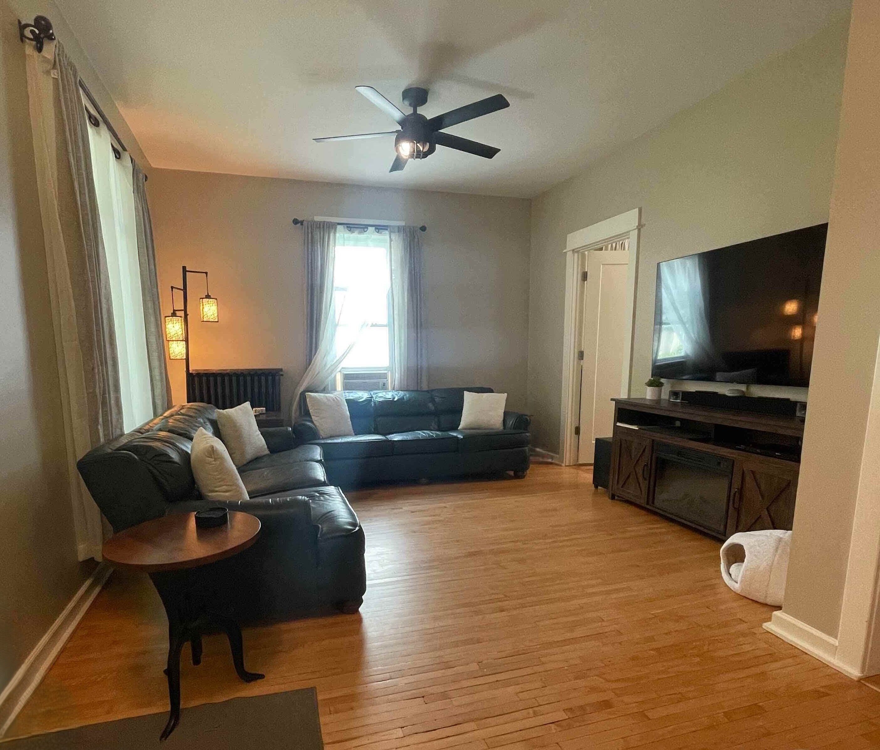 A living room with a sofa, a coffee table, a TV, and a ceiling fan.