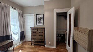 Een kamer met een houten dressoir, een deur, een lijst met een kaart en een inloopkast.