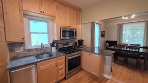 A kitchen with wooden cabinets, a stainless steel refrigerator, a microwave, a stove, and a sink.