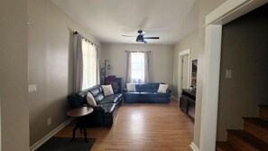 A living room with a sofa, a coffee table, and a ceiling fan.