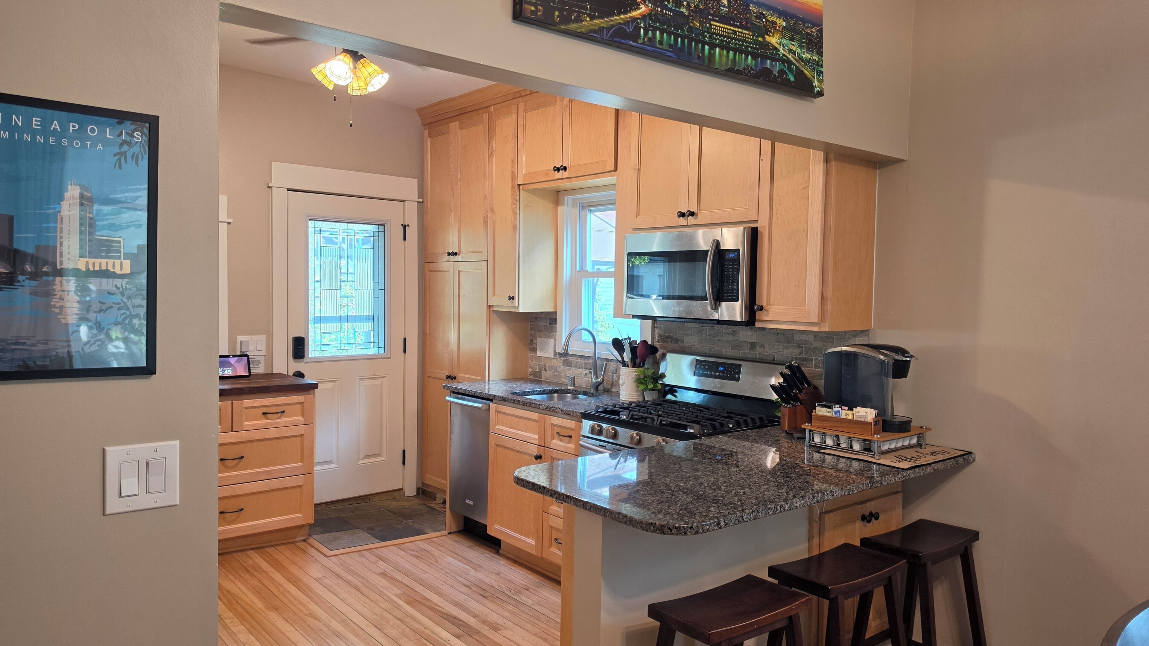 A kitchen with wooden cabinets, a granite countertop, a stainless steel stove, and a microwave.