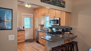 A kitchen with wooden cabinets, a granite countertop, a stainless steel stove, and a microwave. - 4BR NE Minneapolis Home - Sleeps 10, Workspaces, Fenced Yard & EV Charging (Minneapolis)