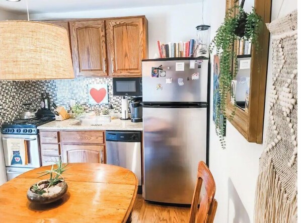 Compact kitchen with a dining area, featuring a stove, microwave, dishwasher, and refrigerator.