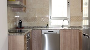 Una cocina moderna con lavavajillas de acero inoxidable, horno empotrado y encimera de granito.