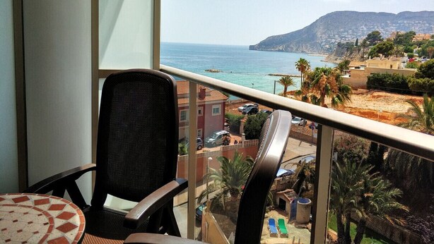 Un balcón con vista al mar y una montaña distante.