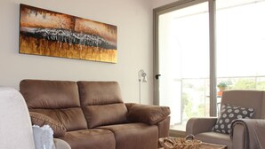 Una sala de estar con un sofá marrón, un sillón gris y una cesta de mimbre sobre una mesa.