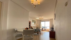 A spacious living area with a dining table, chairs, a sofa, and a balcony with a view. - PLAZA MAYOR - Apartment with beautiful sea and rock views (Calpe / Calp)