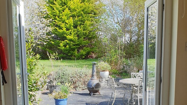 A room with a wooden chair facing a sliding glass door leading to an outdoor patio. - Cottage on Lough Ree / River Shannon in the heart of Ireland (Newtowncashel)