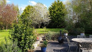 A garden patio with a round table and chairs, surrounded by potted plants and a stone wall. - Cottage on Lough Ree / River Shannon in the heart of Ireland (Newtowncashel)