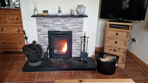 A living room with a fireplace, wooden furniture, a television, and a fireplace mantel. - Cottage on Lough Ree / River Shannon in the heart of Ireland (Newtowncashel)
