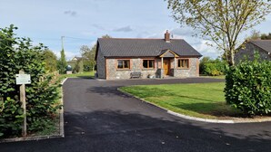 A stone cottage with a tiled roof, a front porch, and a well-maintained lawn. - Cottage on Lough Ree / River Shannon in the heart of Ireland (Newtowncashel)