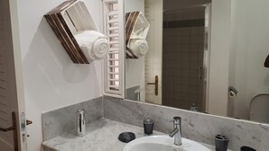A bathroom with a white sink, a mirror, and two towel racks.