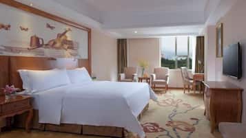 A hotel room with a large bed, a television, a desk, and a view of the outdoors.