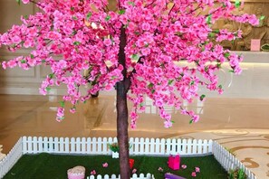 A tree with pink flowers in a white picket fence. - Vienna International Hotel (Beihai Hepu Hesi Shougang Branch) (Hepu)