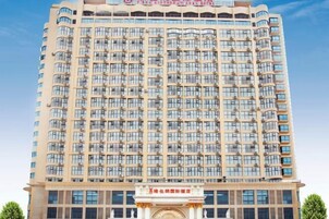 Un hotel moderno de gran altura con una fachada uniforme, múltiples balcones y una entrada central con un arco decorativo.