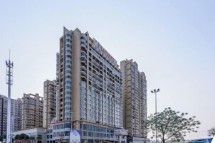 Un hotel de varios pisos con un diseño arquitectónico moderno, que destaca por una entrada en esquina y varios balcones.