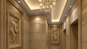 A hallway with marble walls, a chandelier, and classical sculptures.