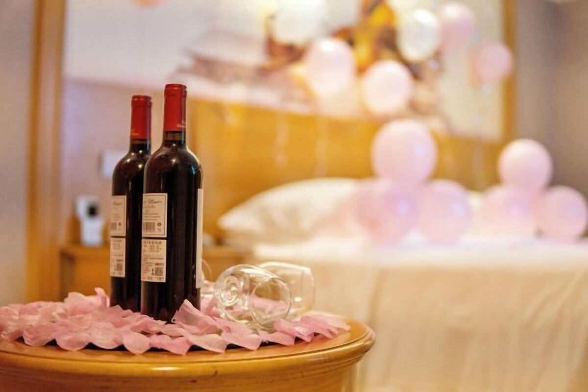 Une table avec deux bouteilles de vin et un verre, posée sur une nappe recouverte de papier rose.