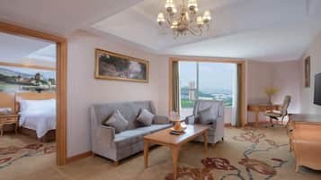 A hotel room with a bed, a sofa, a desk, and a view of a cityscape.