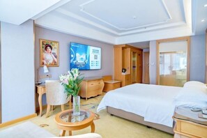 A hotel room with a bed, a desk, a chair, a dresser, a TV, and a window.