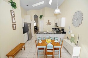 Een moderne keuken met een centraal eiland, witte kasten en een eethoek met een houten tafel en stoelen.