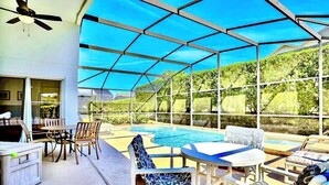 Un espacio al aire libre techado con piscina, asientos y ventilador de techo.