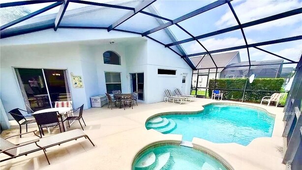 Una piscina interior con techo de cristal, sillones de descanso y un pequeño jacuzzi.