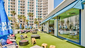 A rooftop lounge area with outdoor seating, a fire pit, and a view of a high-rise building. - A Wave Away 1206-Near Beach-Sleeps 6 (Destin)