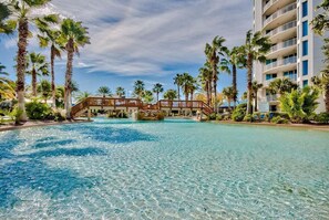 Piscina de resort con agua cristalina, rodeada de palmeras y un puente de madera.