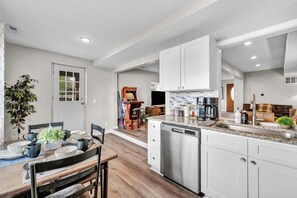A modern kitchen with white cabinets, a dishwasher, and a coffee maker.